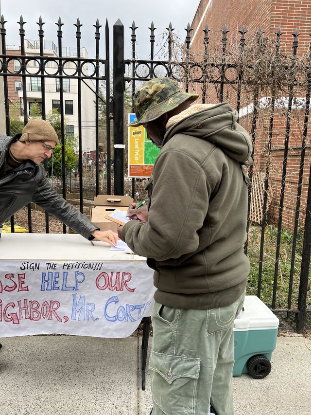 A neighbor stopped by the Warren St. Marks Community Garden to sign a petition to keep Ray Cortez in his home.